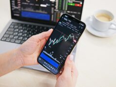 Margin Trading in Crypto – Opportunities and Risks a person holding a cell phone in front of a laptop