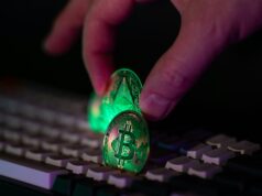 How to Avoid Common Crypto Scams and Rug Pulls Hand placing glowing crypto coins on a keyboard.